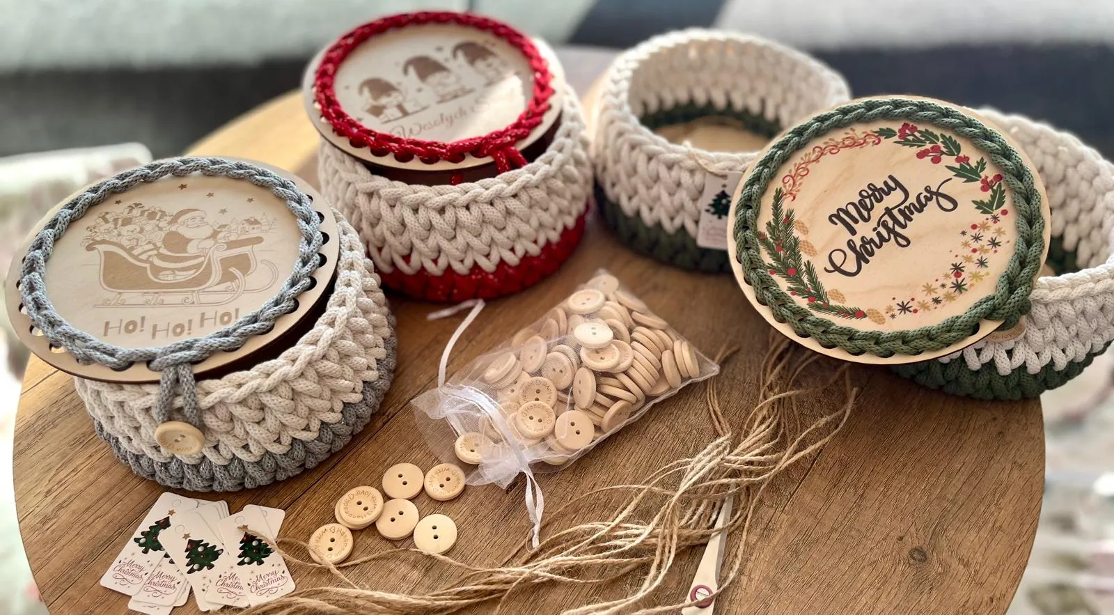 Świąteczne koszyczki z pokrywkami: Mikołaj, krasnale i wianek Merry Christmas, obok drewniane guziki
